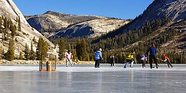 People playing ice hockey on a frozen, snow free Tenaya Lake in Yosemite National Park.