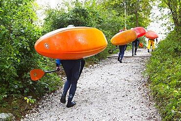 Kayakers carrying their colorful kayaks to river Soca near Bovec, Triglav, Slovenia