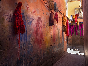 Colorful fabrics hanging in narrow alley decorated with handprints, Marrakesh, Morocco