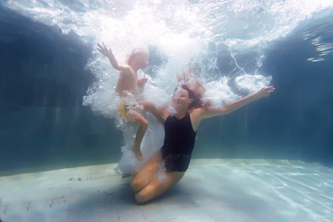 Underwater view of mother and son swimming in swimming pool