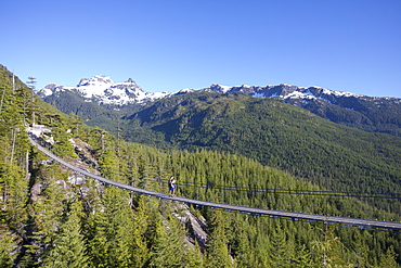 Distant view shot of couple on rope bridge at top of Sea to Sky Gondola, Vancouver, British Columbia, Canada