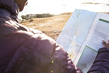 Over the shoulder view of single woman checking map, Kittery, Maine, USA