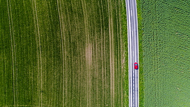 Aerial view of car driving down road surrounded by fields, Genolier, Vaud Canton, Switzerland