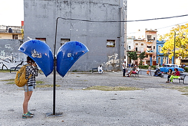 Side view of female tourist using payphone, Havana, Cuba