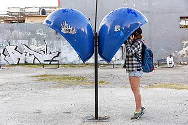 Side view of female tourist using payphone, Havana, Cuba