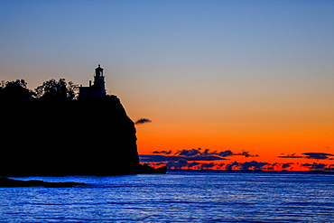 Silhouette of lighthouse on coastal cliff at sunset, Two Harbors, Minnesota, USA