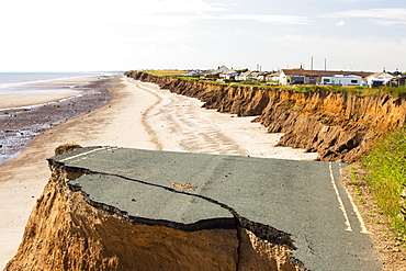 A collapsed coastal road at between Skipsea and Ulrome on Yorkshires East Coast, near Skipsea, UK. The coast is composed of soft boulder clays, very vulnerable to coastal erosion. This section of coast has been eroding since Roman times, with many villages having disappeared into the sea, and is the fastest eroding coast in Europe. Climate change is speeding up the erosion, with sea level rise, increased stormy weather and increased heavy rainfall events, all playing their part.