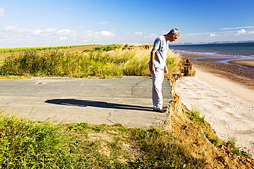 A collapsed coastal road at near Aldbrough on Yorkshires East Coast, near Skipsea, UK. The coast is composed of soft boulder clays, very vulnerable to coastal erosion. This section of coast has been eroding since Roman times, with many villages having disappeared into the sea, and is the fastest eroding coast in Europe. Climate change is speeding up the erosion, with sea level rise, increased stormy weather and increased heavy rainfall events, all playing their part.