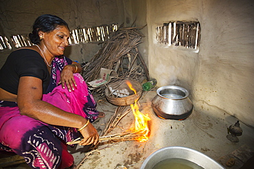 A villager woman in a remote subsistence farming village on an island in the Sundarbans, the Ganges Delta in Eastern India that is very vulnerable to sea level rise. She is cooking on a traditional clay oven, fueled by biofuel (rice stalks), low carbon cooking.