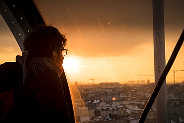 Man looking through window at sunset at view of Paris, France in Centre Georges Pompidou