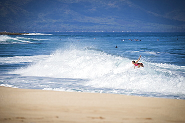 Distant view of female surfer surfing near beach