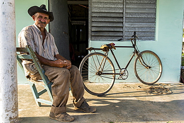 Man sitting in chair and posing for portrait outside home, Vinales, Pinar del Rio Province, Cuba