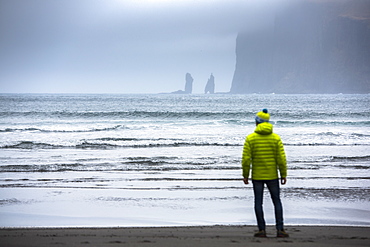 Rear view of man standing on seashore, Faroe Islands, Denmark