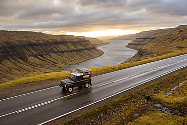 4x4 car driving along road on seashore, Faroe Islands, Denmark