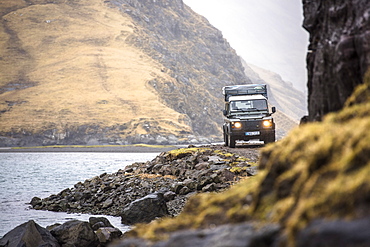 Front view of 4x4 car driving along coastline, Faroe Islands, Denmark