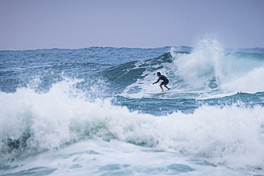 Man surfing at dusk on messy waves on North Shore of Oahu, Hawaii, USA