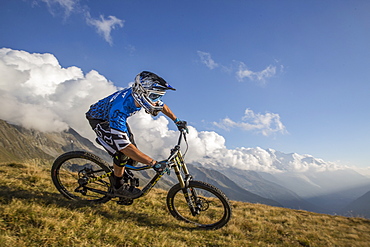 Mountain landscape with downhill biker cruising down single track at end of day in Chamonix valley, Chamonix, Haute Savoie, France