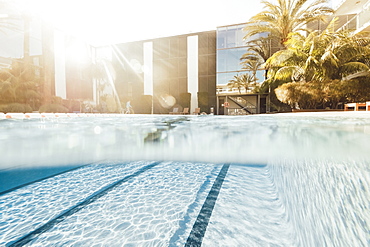 Backlit half in/half out picture of swimming pool in front of hotel and palm trees, Mallorca, Balearic Islands, Spain