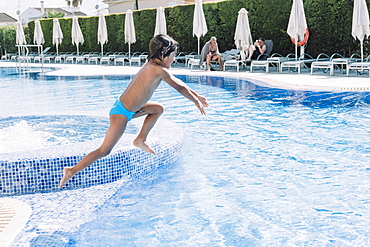 A kid jumps in a hotel pool, Mallorca, Balearic Islands, Spain