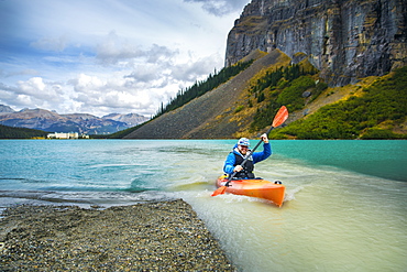 Male kayaker paddling by riverbank on glacial river, Lake Louise, Alberta, Canada