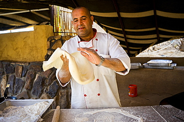 Chef throwing bread dough ofÂ shrakÂ (markook)Â to make it very thin before cooking on hotÂ sajÂ (orÂ domed ironÂ griddle), Wadi Rum Village, Aqaba Governorate, Jordan