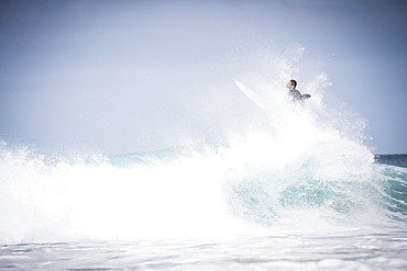 Male surfer doing trick off wave on North shore of Oahu at daytime, Hawaii, USA