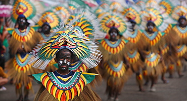 Boy with painted face in tribal costume in front of large group of people in tribal costumes during Ati Atihan Festival, Kalibo, Aklan, Panay Island, Philippines