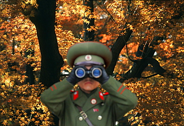 North Korean soldier looking through binoculars against autumn tree, Kumgang San, Kumgang, North Korea