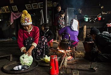 Three generation family sitting around campfire in small rural house, Myanmar, Shan, Myanmar