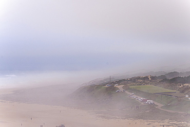 View of sandy beach and hill in fog at morning, Nazare, Leiria, Portugal