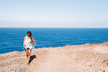 Woman walking on flat stretch of coast with ocean in background at daytime, Tenerife, Canary Islands, Spain