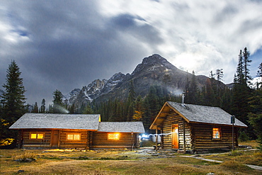 Illuminated Elizabeth Parker Hut at dusk with Mount Schaffer in background, Field, British Columbia, Canada