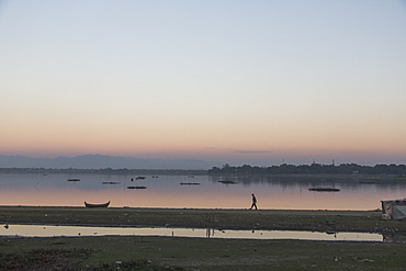 Clear sky over silhouette of person walking along lakeshore at dusk, Mandalay, Mandalay District, Myanmar