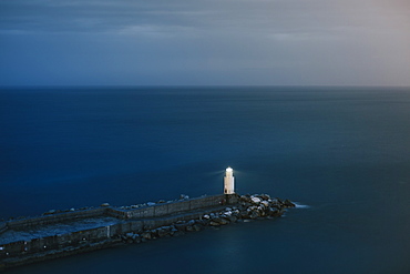 Tranquil seascape with lone lighthouse and pier at dusk, Camogli, Liguria, Italy