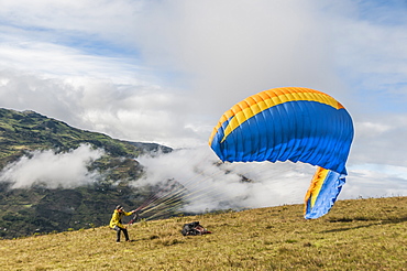 Distant view of adventurous man getting ready to?paraglide?down a mountain in?Paute Canton, Azuay Province, Ecuador