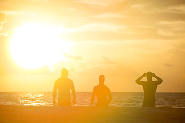 View of silhouettes of three men in swimming caps on beach at sunrise,?Playa?del?Carmen,?Quintana?Roo, Mexico