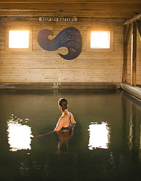 A woman soaks in an indoor hot spring in an old barn building, Summer Lake, Oregon, USA