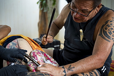 Side view of Hawaiian tattoo artist making tattoo, Oahu, Hawaii Islands, USA