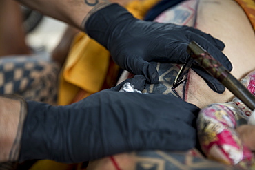 Close-up?shot of hands of Hawaiian tattoo artist making tattoo, Oahu, Hawaii Islands, USA