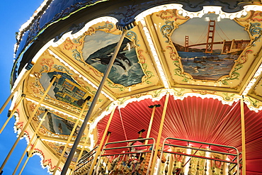 An old carousel, painted with life scenes of San Francisco in an end-of-day light, Pier 39, San Francisco, California, USA