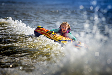 Front view of girl having fun tubing on river