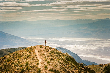 A man stands on a peak looking out over Death Valley at Dantes View, California, USA