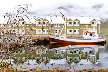 Reflections of buildings and boats in the ocean at the port of Siglufjordur, Iceland