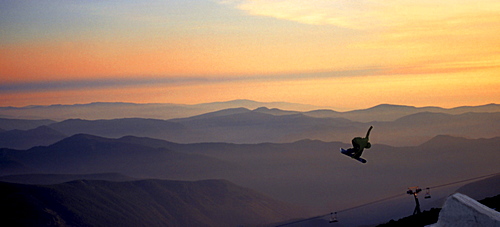 A snowboarder pulls a grab during sunset at Mt. Hood, Timberline.