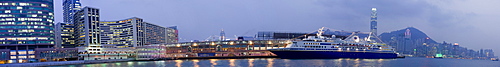 Night time view of a cruise ship docked at Tain Sha Tsui, Kowloon, with the buildings of central Hong Kong visible in the background, Hong Kong, China.