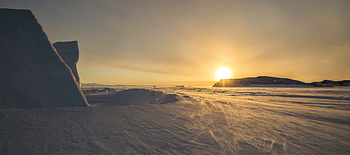 Sunset behind an iceberg looking north across the frozen surface of the Ross Sea, Antarctica.