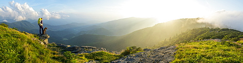 A panorama of a woman and her dog watching the sunset on Grassy Ridge while backpacking on the Roan Highlands near  Bakersville, North Carolina.