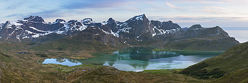 Mountains rise over calm water of Flakstadpollen, Flakstadøy, Lofoten Islands, Norway