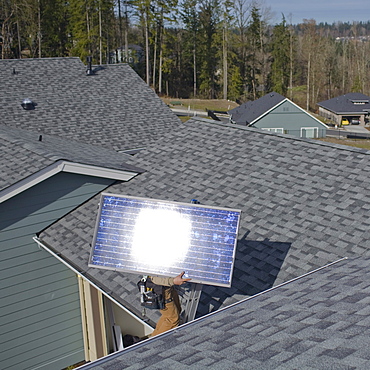 A worker installs solar panels on a rooftop in Redmond, WA.