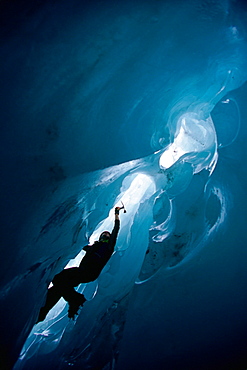 An ice climber climbs out of an ice cave on the Franz Josef Glacier on New Zealand's South Island.